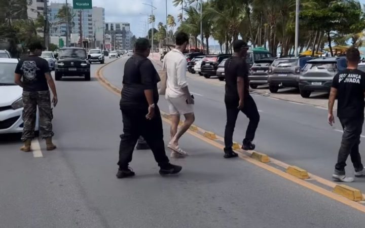 Influenciador Rico Melquiades atravessa a rua cercado por cinco seguranças particulares